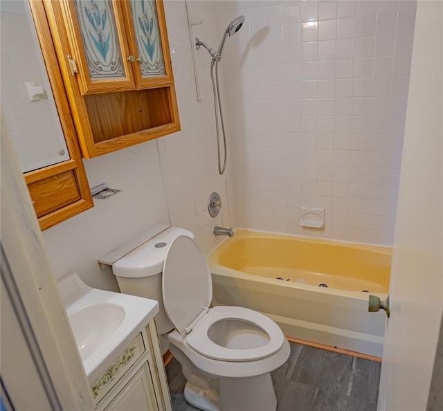 full bathroom with hardwood / wood-style floors, vanity, tiled shower / bath combo, and toilet