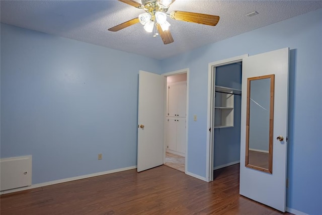 unfurnished bedroom featuring a closet, a textured ceiling, dark hardwood / wood-style floors, and ceiling fan