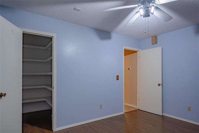 unfurnished bedroom with a textured ceiling, a closet, ceiling fan, and dark wood-type flooring