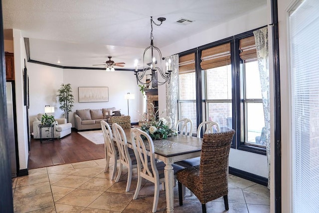 dining space with crown molding, light tile patterned floors, ceiling fan with notable chandelier, baseboards, and visible vents