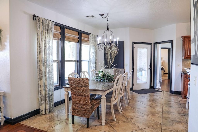 dining area with a textured ceiling, visible vents, baseboards, an inviting chandelier, and light tile patterned floors