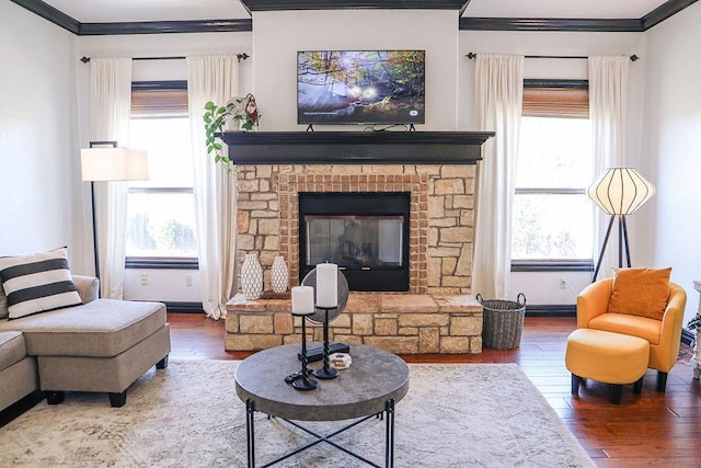 living area featuring a stone fireplace, baseboards, hardwood / wood-style flooring, and ornamental molding
