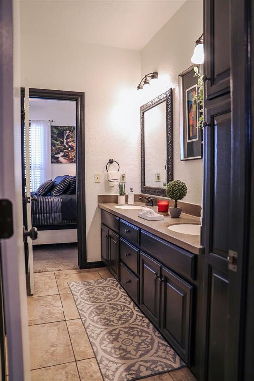 ensuite bathroom with tile patterned flooring, a sink, double vanity, and ensuite bathroom