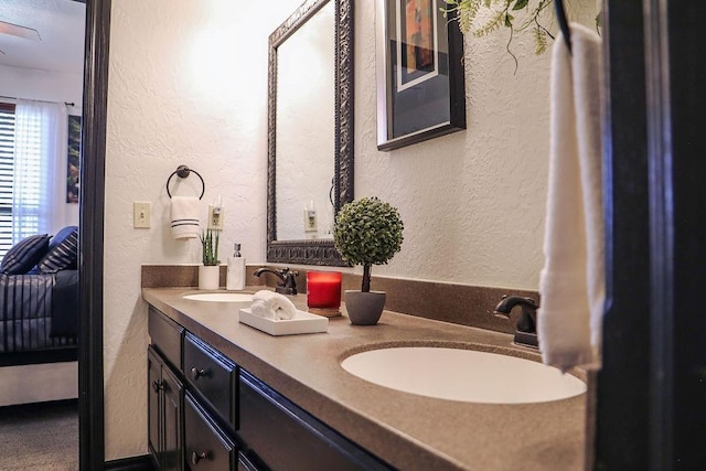 full bath featuring a sink, a textured wall, and ensuite bathroom