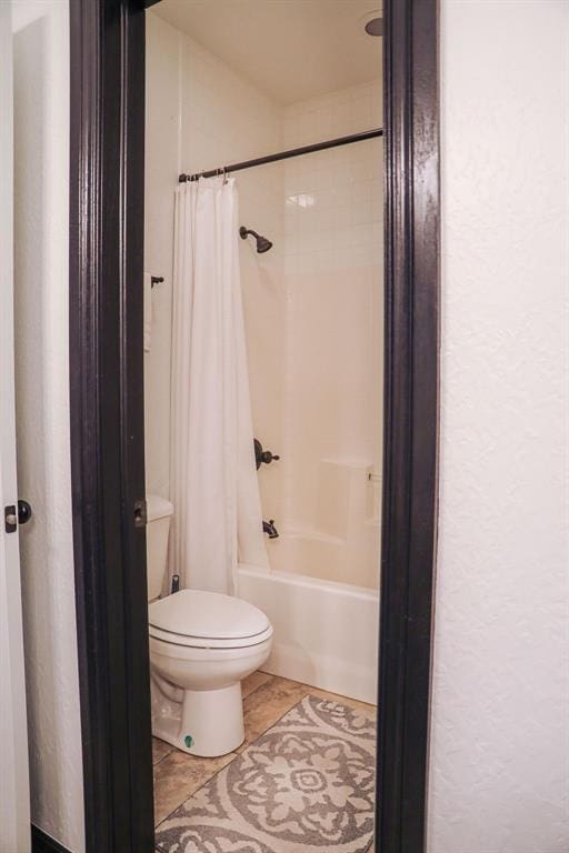 bathroom with toilet, shower / bath combination with curtain, and tile patterned flooring