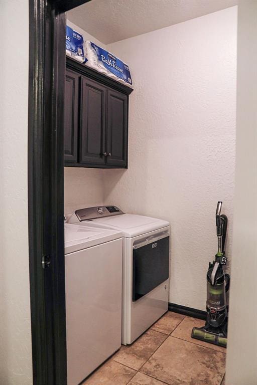 laundry room with light tile patterned floors, cabinet space, a textured wall, and separate washer and dryer