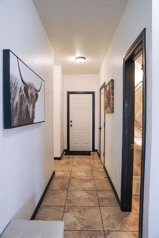 hallway featuring baseboards and light tile patterned floors