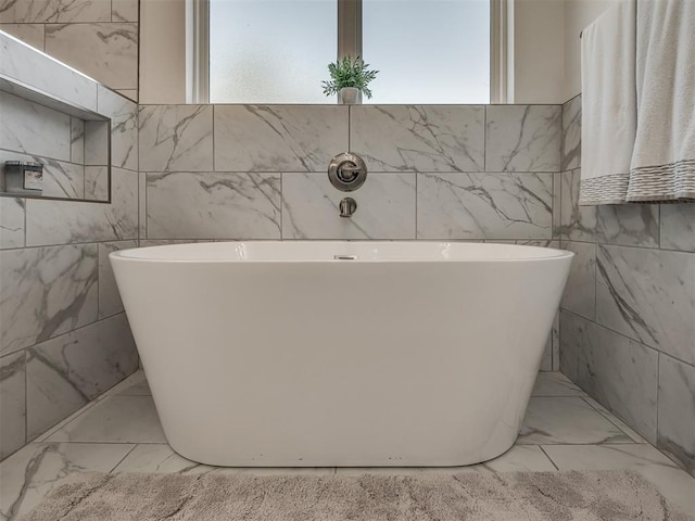 bathroom featuring a bath and tile walls