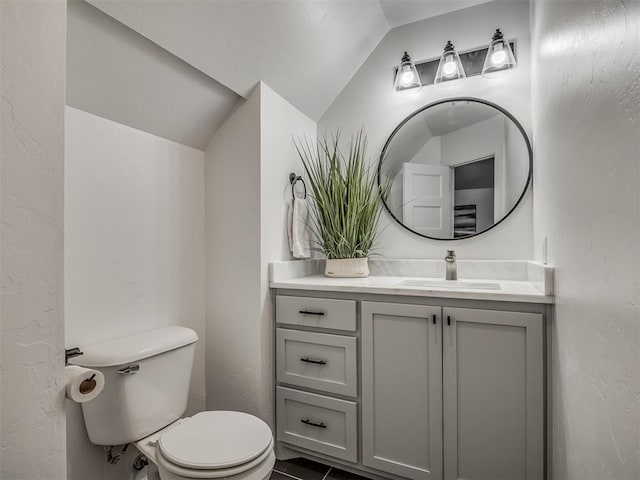 bathroom with vanity, toilet, and lofted ceiling