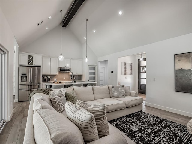 living room with sink, beamed ceiling, high vaulted ceiling, and hardwood / wood-style flooring