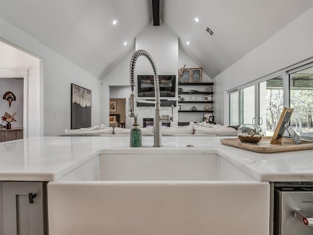 kitchen with beamed ceiling, sink, a fireplace, and high vaulted ceiling