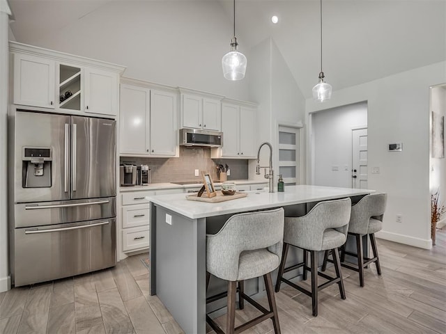 kitchen with white cabinetry, stainless steel refrigerator with ice dispenser, a kitchen island with sink, and light hardwood / wood-style flooring