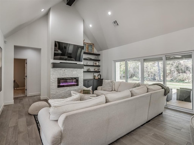 living room featuring wood-type flooring, a fireplace, and high vaulted ceiling