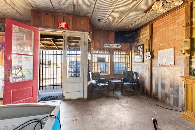 interior space featuring concrete flooring, ceiling fan, wooden ceiling, and wood walls