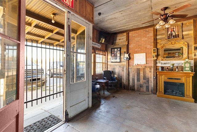 interior space with ceiling fan, a fireplace, a healthy amount of sunlight, and wood walls