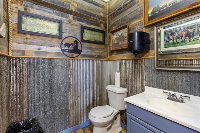 bathroom featuring vanity, toilet, and wood walls