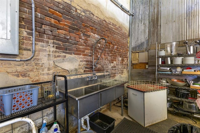 kitchen with concrete floors, electric panel, and brick wall