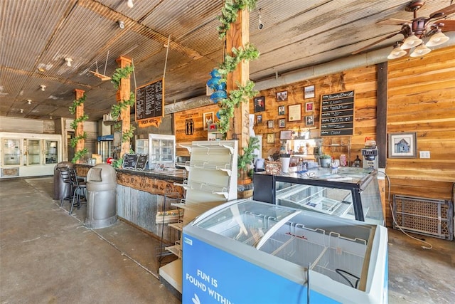 interior space with ceiling fan and wood walls