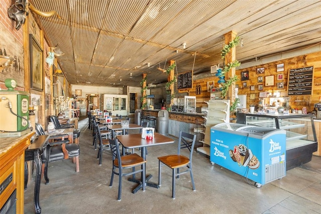 dining area featuring wood walls and concrete flooring