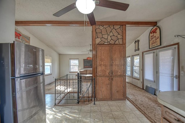 kitchen featuring stainless steel refrigerator, ceiling fan, lofted ceiling with beams, and a textured ceiling