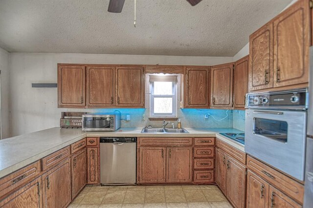 kitchen with sink, ceiling fan, a textured ceiling, appliances with stainless steel finishes, and light tile patterned flooring