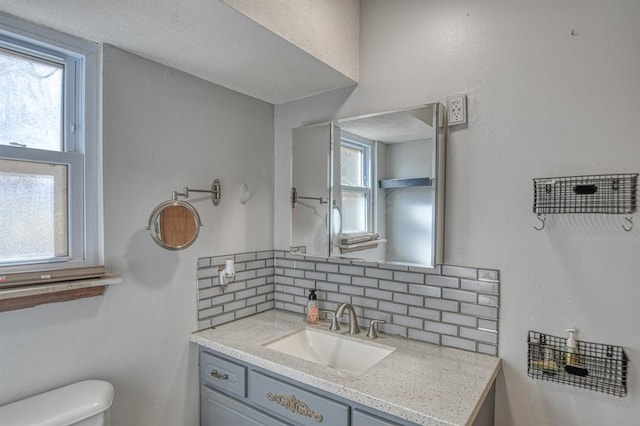 bathroom with vanity, tasteful backsplash, and toilet