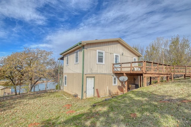 rear view of property with a lawn, central AC unit, and a deck