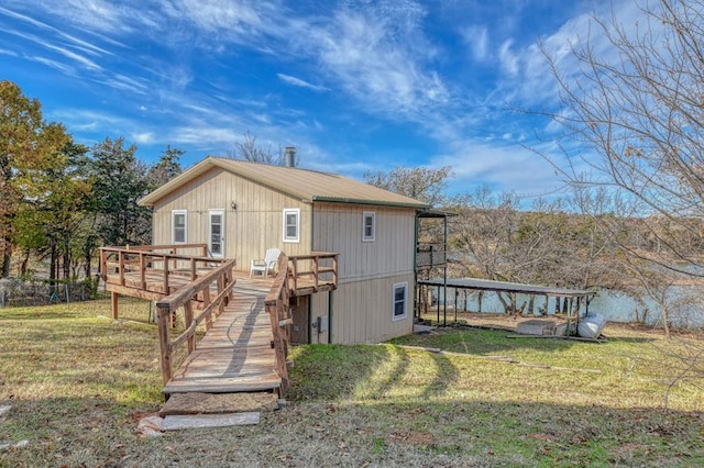 rear view of house featuring a wooden deck and a yard