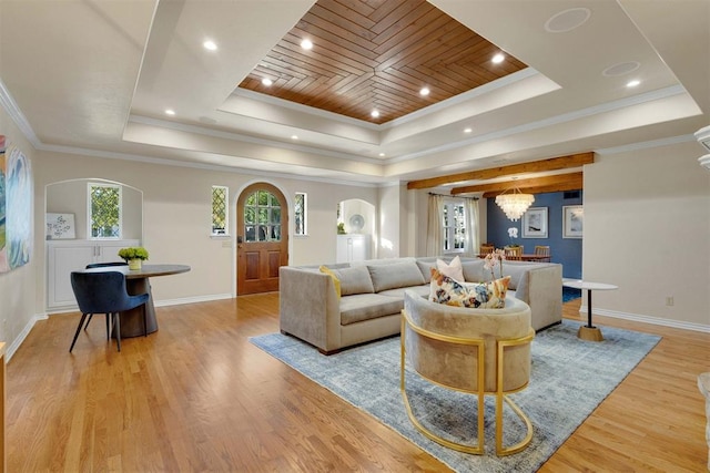 living room featuring light hardwood / wood-style floors, a raised ceiling, and ornamental molding