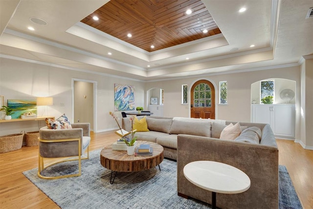 living room with a raised ceiling, crown molding, and light hardwood / wood-style flooring