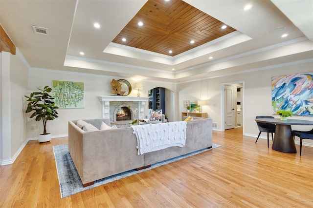 living room with light hardwood / wood-style floors, a raised ceiling, ornamental molding, and wooden ceiling