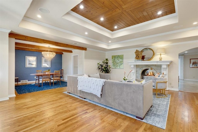 living room featuring wooden ceiling, crown molding, light hardwood / wood-style flooring, a tray ceiling, and a notable chandelier