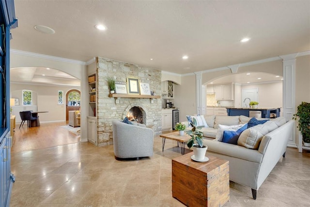 living room featuring a stone fireplace, built in features, and ornamental molding