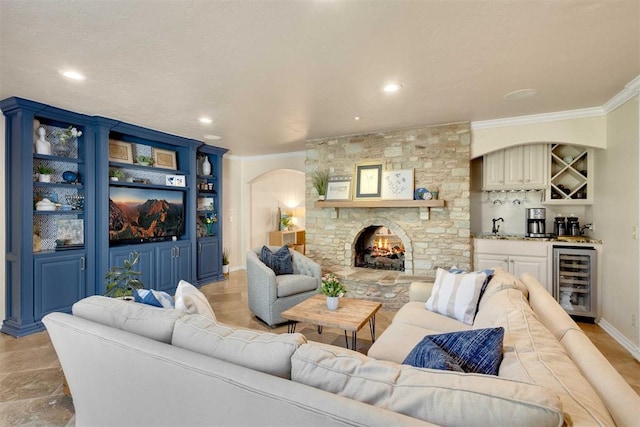 living room with a fireplace, wine cooler, wet bar, and crown molding