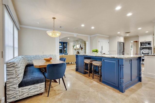 kitchen featuring stainless steel appliances, blue cabinets, crown molding, decorative light fixtures, and white cabinets