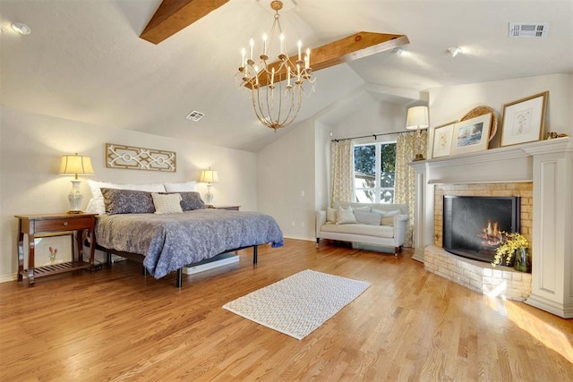 bedroom featuring a brick fireplace, vaulted ceiling with beams, light wood-type flooring, and a chandelier