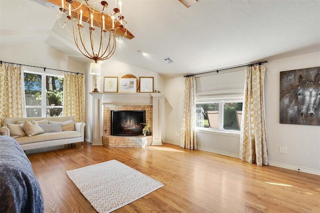 living room with a brick fireplace, plenty of natural light, lofted ceiling, and hardwood / wood-style flooring