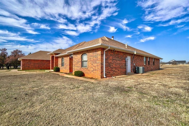 view of side of property featuring a yard and central AC unit