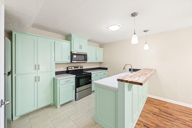 kitchen featuring sink, hanging light fixtures, stainless steel appliances, wood counters, and light hardwood / wood-style flooring