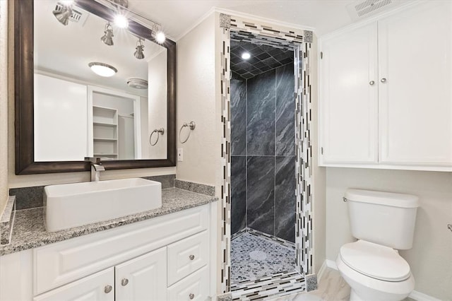 bathroom featuring vanity, toilet, a shower with shower door, and ornamental molding