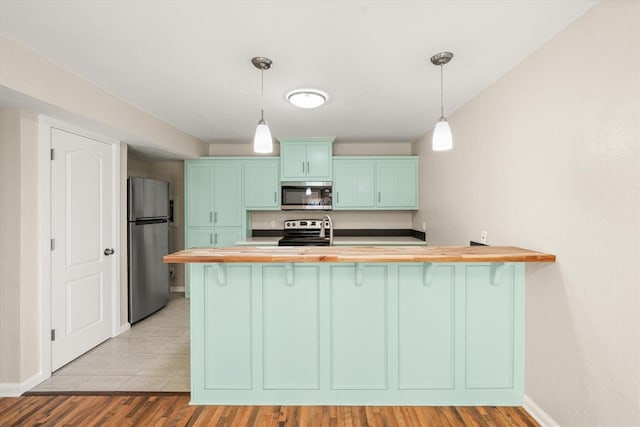 kitchen featuring pendant lighting, light hardwood / wood-style floors, kitchen peninsula, and stainless steel appliances