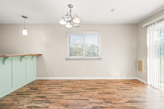 unfurnished dining area featuring wood-type flooring and an inviting chandelier