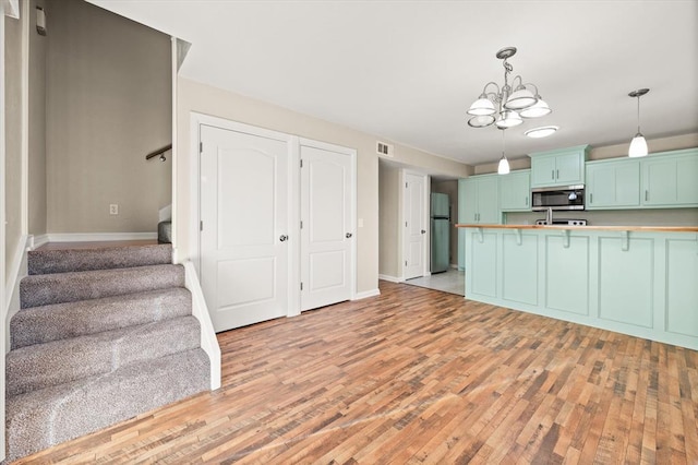 kitchen with hanging light fixtures, light hardwood / wood-style flooring, a chandelier, appliances with stainless steel finishes, and green cabinetry