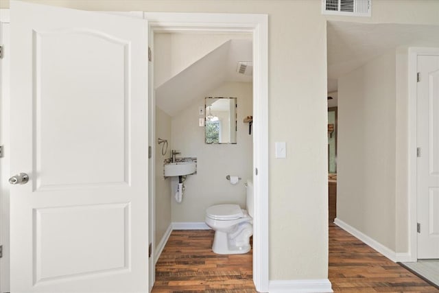 bathroom with hardwood / wood-style floors, toilet, and lofted ceiling