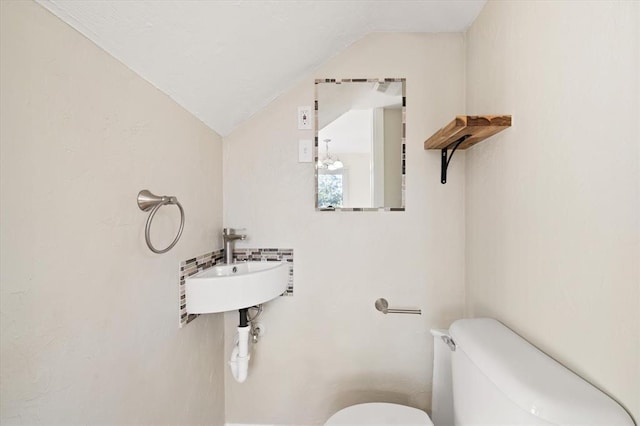 bathroom featuring toilet, vaulted ceiling, and sink