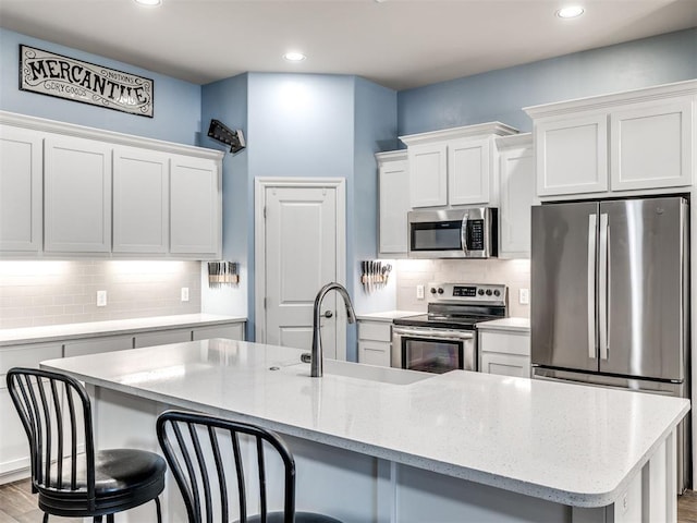 kitchen with white cabinetry, sink, appliances with stainless steel finishes, and an island with sink