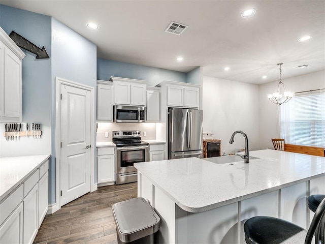 kitchen with a kitchen breakfast bar, stainless steel appliances, sink, decorative light fixtures, and a chandelier