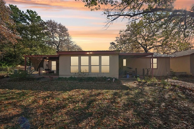 back house at dusk with a yard and a patio