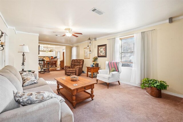 carpeted living room featuring ceiling fan with notable chandelier and ornamental molding