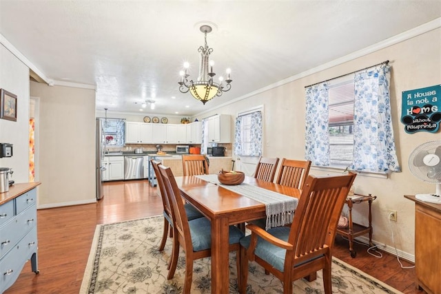 dining space featuring light wood-type flooring, ornamental molding, and an inviting chandelier